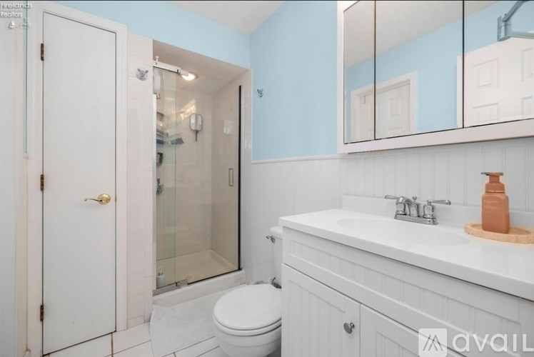 A bathroom with a toilet, sink, and mirror.