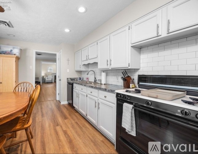 A kitchen with white cabinets and a wooden table.