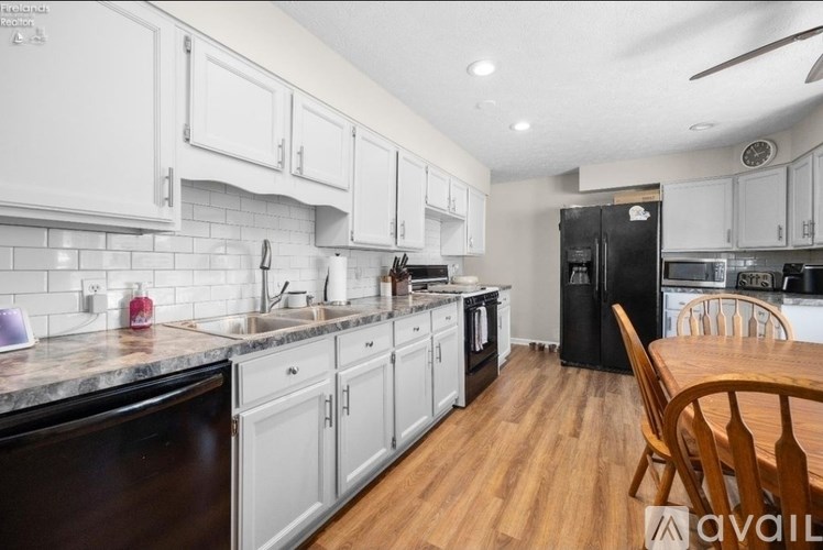 A kitchen with white cabinets and a black fridge.