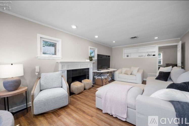 A living room with a grey sofa, a grey armchair, a white couch, and a fireplace.