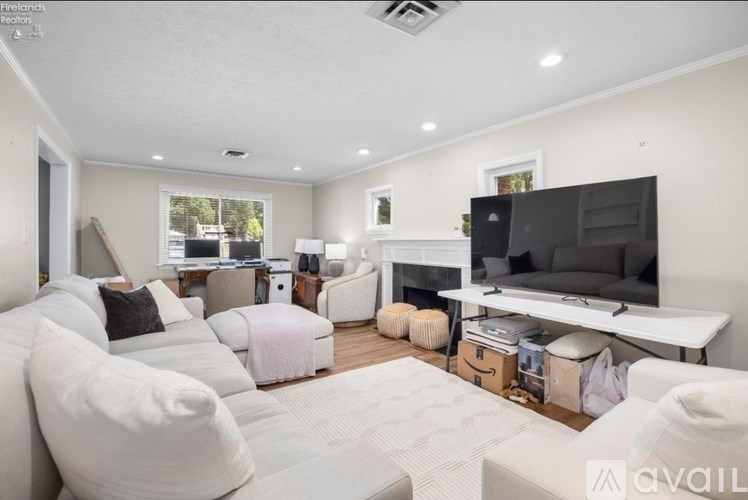 A living room with a white couch and a television on a white stand.