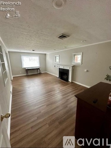 A living room with a fireplace and wooden floors.