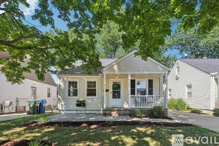 A house with a front porch is surrounded by greenery.