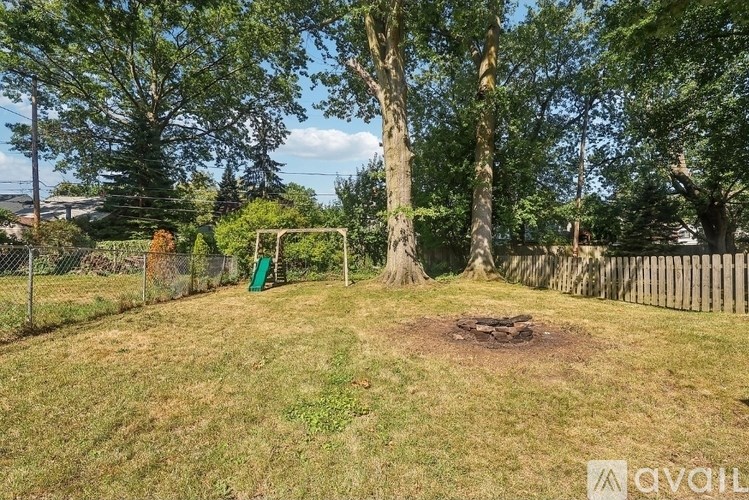 A backyard with a swing set and a tree.