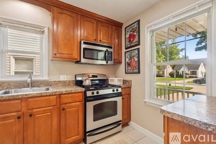 A kitchen with wooden cabinets and a window overlooking a lawn.