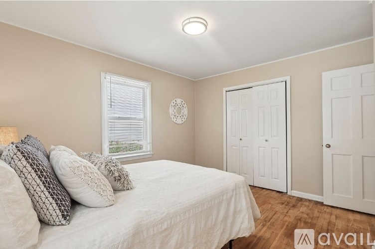 A bedroom with a bed, two pillows, a window, and a wall clock.