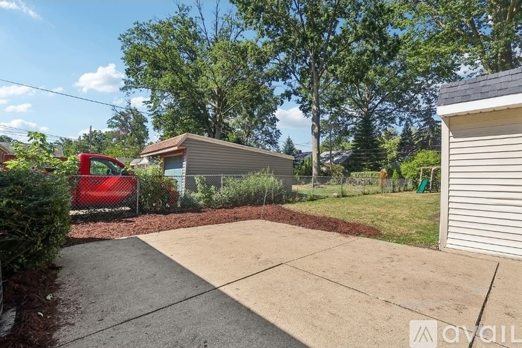 A red car is parked in a driveway next to a house.