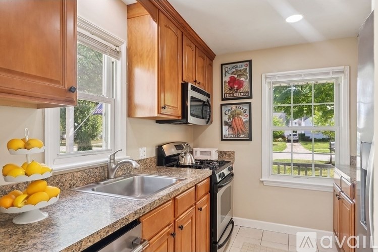 A kitchen with wooden cabinets and a window showing a view of a street.