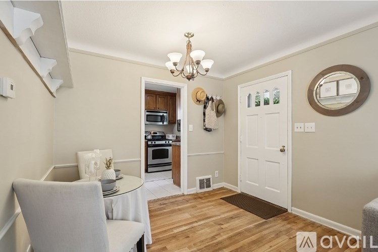A dining room with a table set for two and a chandelier hanging from the ceiling.