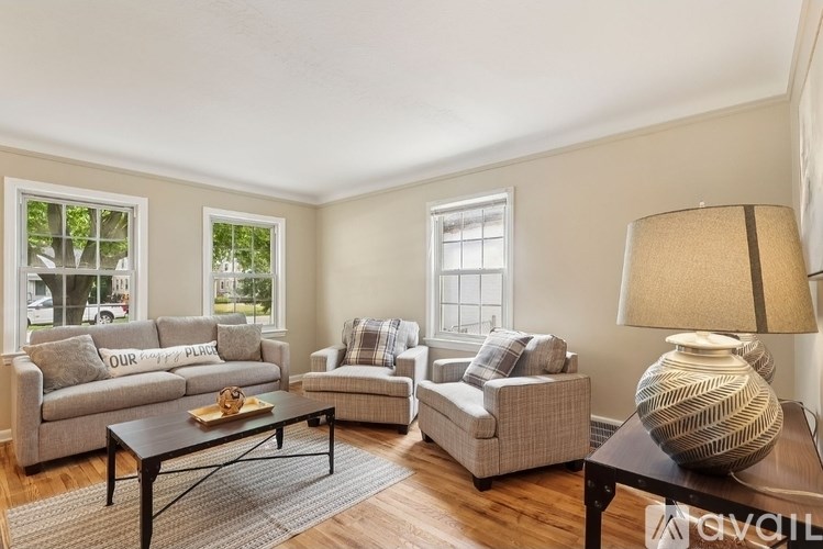 A living room with a grey couch, a grey chair, a grey ottoman, a coffee table, a lamp, and a vase.