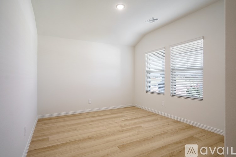 A room with wooden flooring and a window with blinds.
