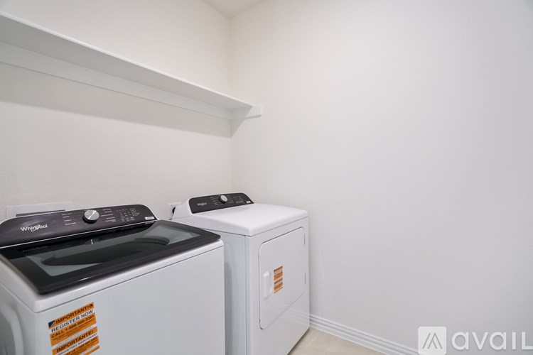 A white dryer and washer are in a small, white-walled laundry room.