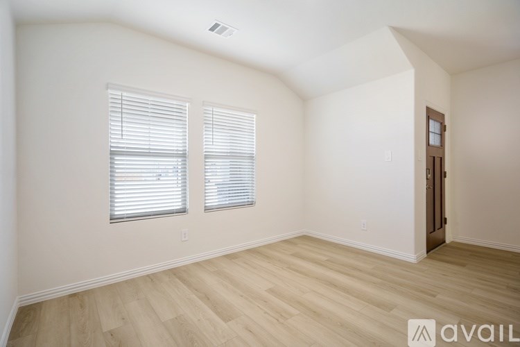 A room with wooden flooring and a window with blinds.