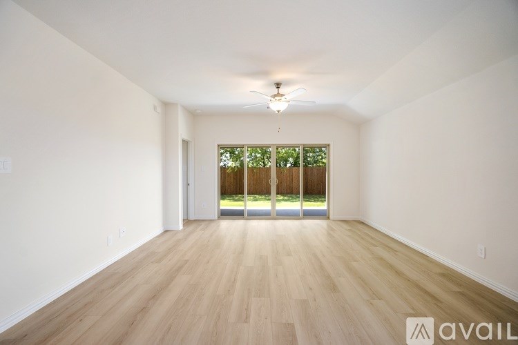 A spacious room with wooden flooring and a ceiling fan.