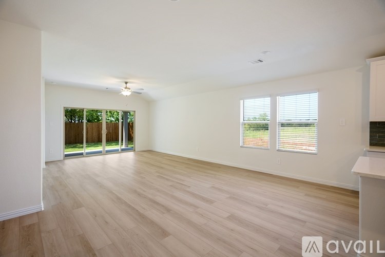 A spacious room with wooden flooring and sliding glass doors.