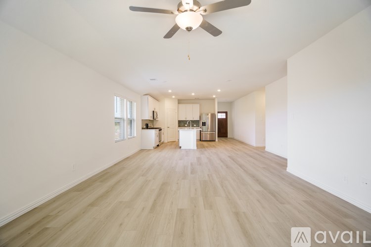 A spacious room with a ceiling fan and wooden flooring.