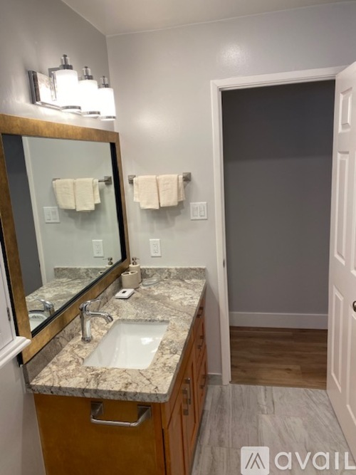 A bathroom with a marble countertop and a large mirror.