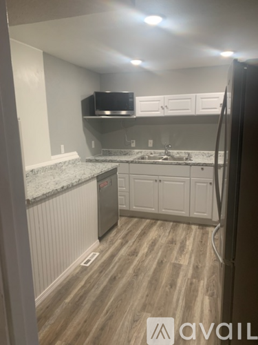 A kitchen with a granite counter top and wooden flooring.