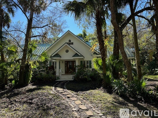 A house with a green roof is surrounded by trees.