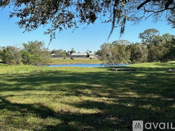 A grassy field with trees and a building in the distance.