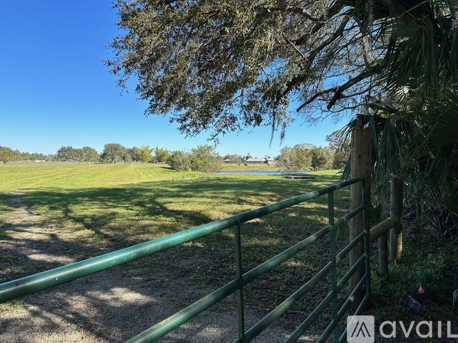A green fence in front of a grassy field.
