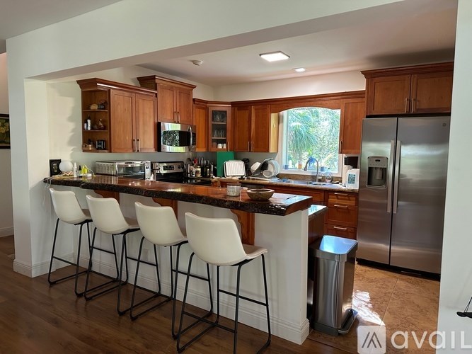 A kitchen with a bar area and white chairs.