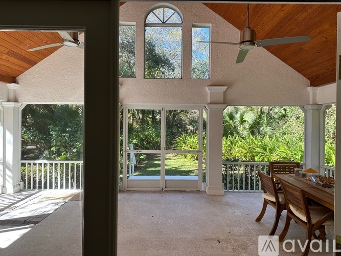 A sunroom with a table and chairs and a ceiling fan.