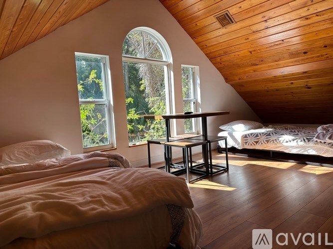 A bedroom with wooden walls and a large window with a view of trees.