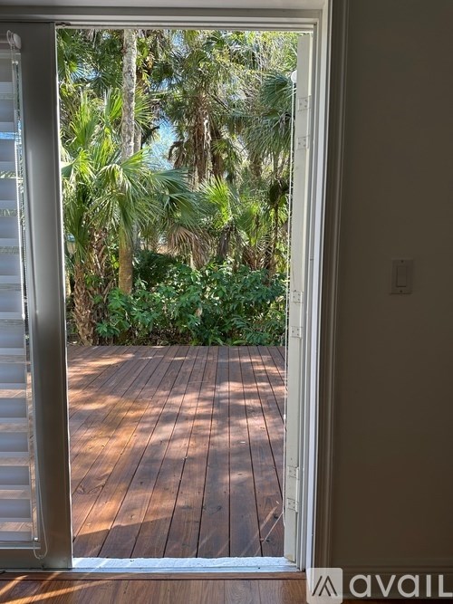 A wooden deck is seen through an open door.
