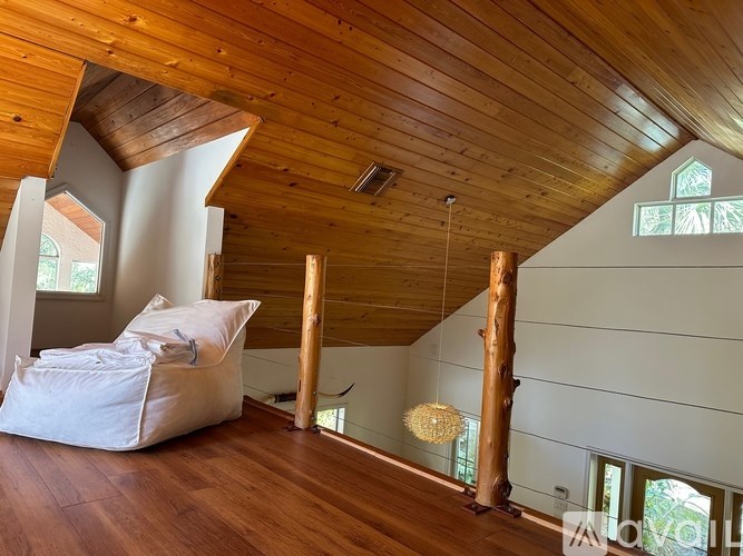 A room with wooden floors and a wooden ceiling with a white bean bag on the floor.