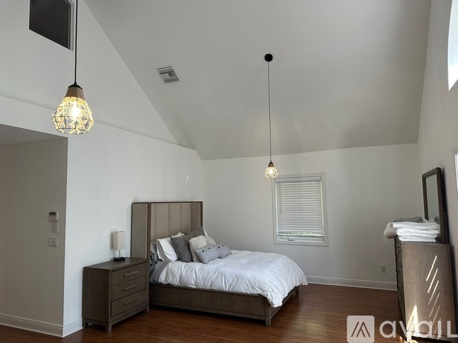 A bedroom with a bed, nightstand, and two hanging lights.