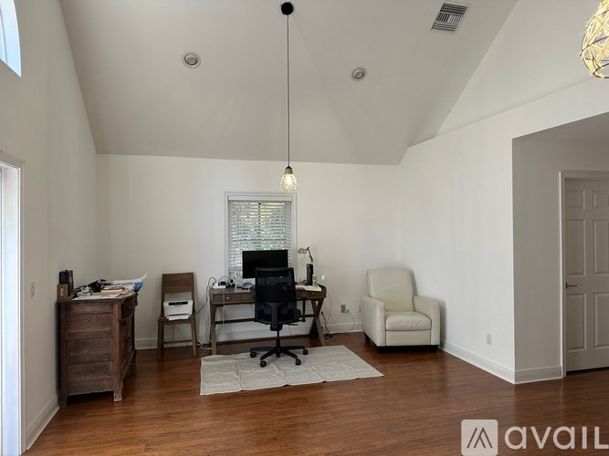 A room with a desk, chair, and a hanging light fixture.