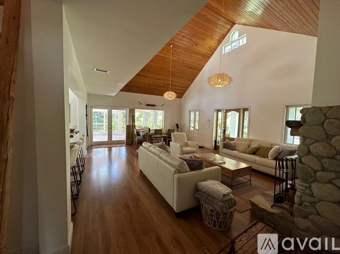 A spacious living room with white furniture and wooden floors.