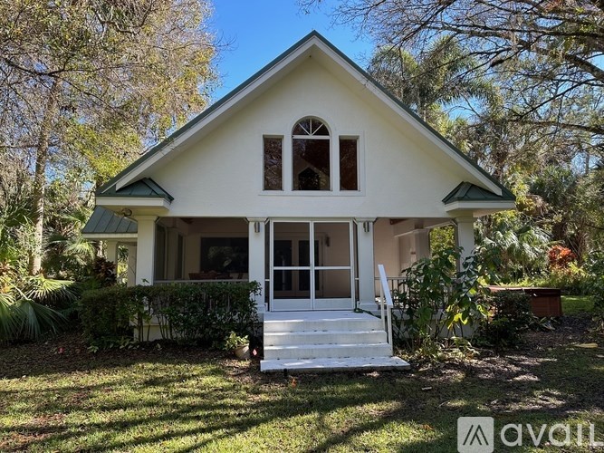 A white house with a green roof and a porch.