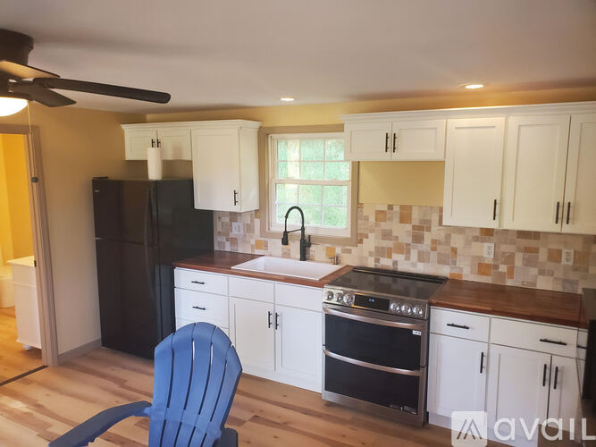 A kitchen with a blue chair in front of a black fridge.