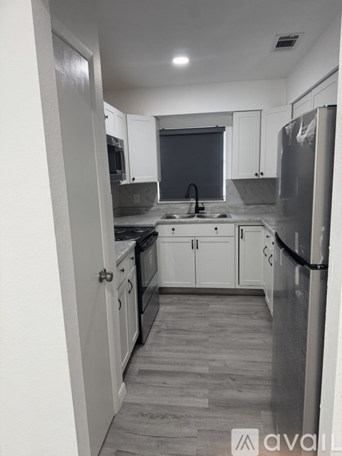 A kitchen with white cabinets and a black fridge.