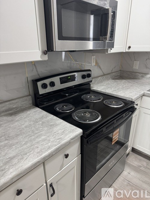 A black stove top oven with four burners and a microwave above it.