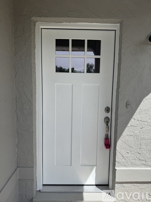 A white door with a glass window and a red handle.