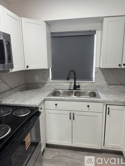 A kitchen with white cabinets and a black stove top oven.