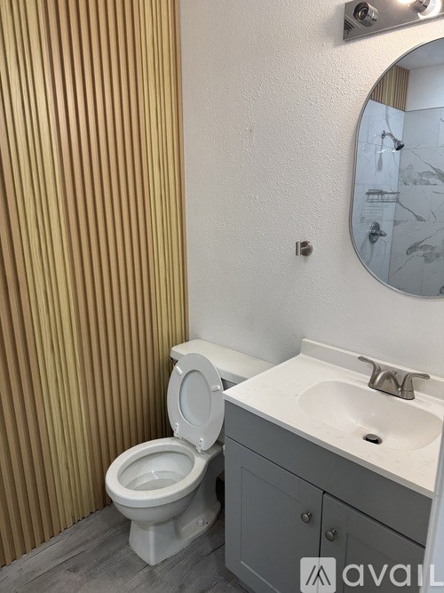 A bathroom with a toilet, sink, and mirror.