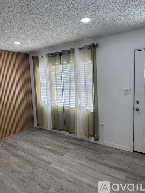 A room with a white door and a window with curtains.