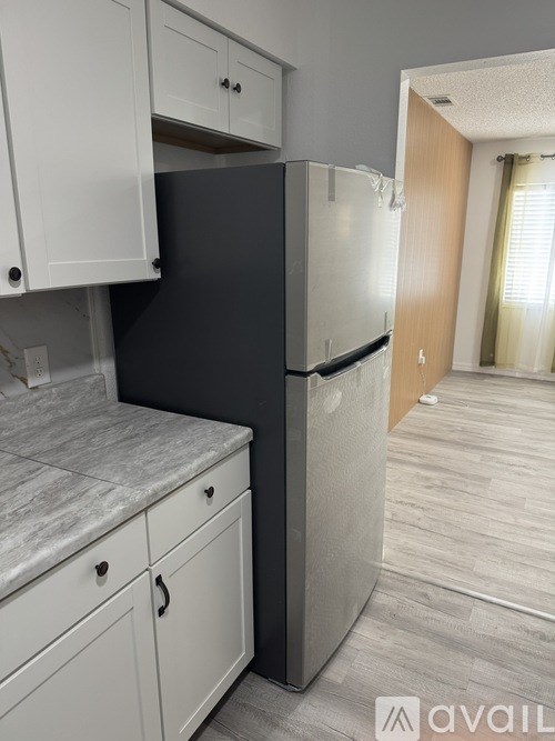 A kitchen with a black fridge and white cabinets.