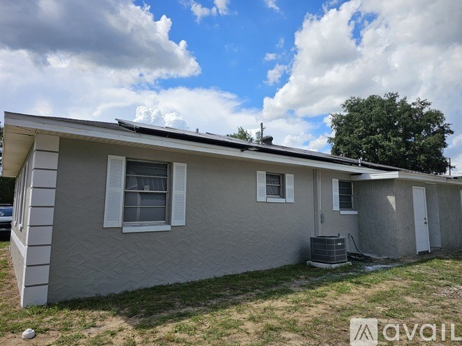 A house with a grey roof and white walls is for sale.