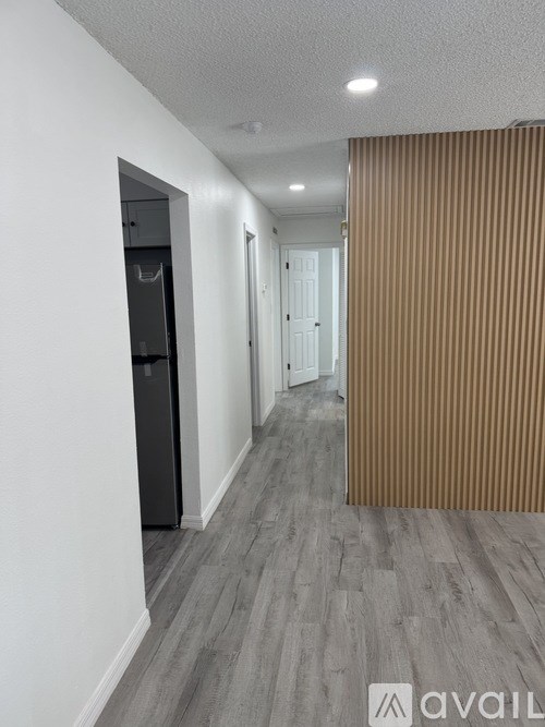 A hallway with a refrigerator on the left and a door on the right.