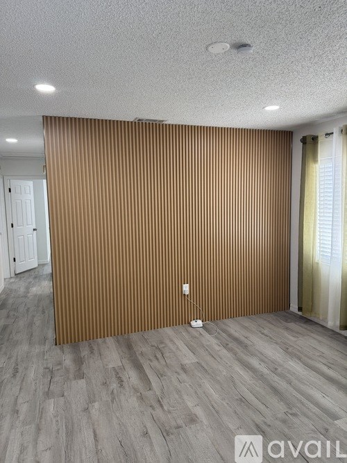 A room with a wooden wall and a grey floor.