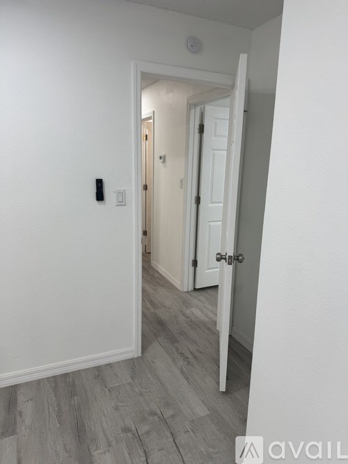 A hallway with a door on the right and a light switch on the wall.