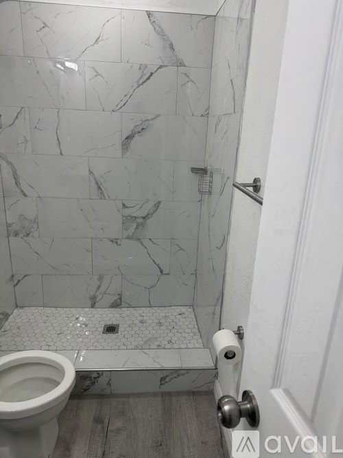 A bathroom with a marble tile shower and toilet.