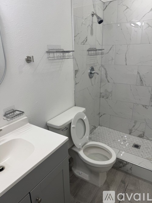 A white toilet is in a bathroom with marble tile walls.