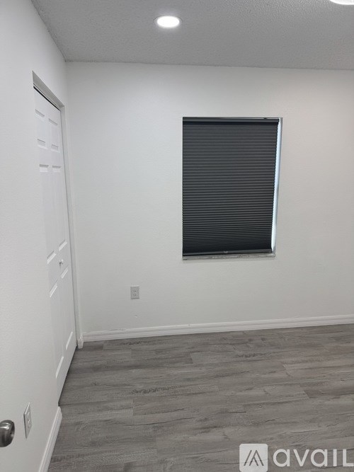 A room with a door, window, and wooden floor.