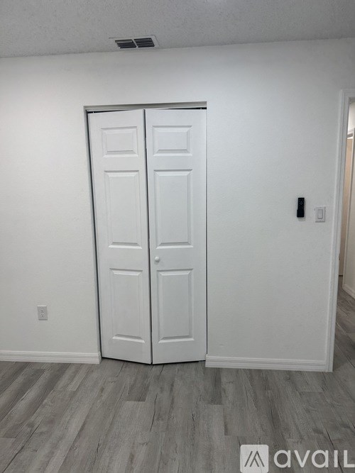 A white double door is closed in a room with wooden flooring.